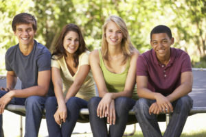 Four Teenage Friends Sitting On Trampoline In Garden