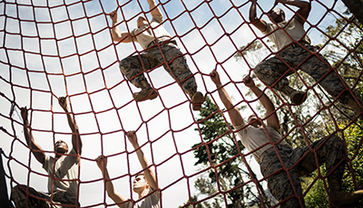 Military soldiers climbing rope during obstacle course