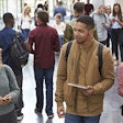 Students holding tablets and phone talk in university lobby