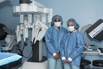 First-year Howard University students Lonna Algee, left, and Madison Pina observe Frederick in the operating room.
