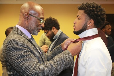 UCF Assistant Vice President A.J. Range presents a tie to Alexander Dorsey-Tarpley, who is being honored during a Men in Maroon event.