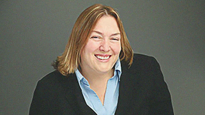 Professional woman in black blazer and blue shirt smiling warmly