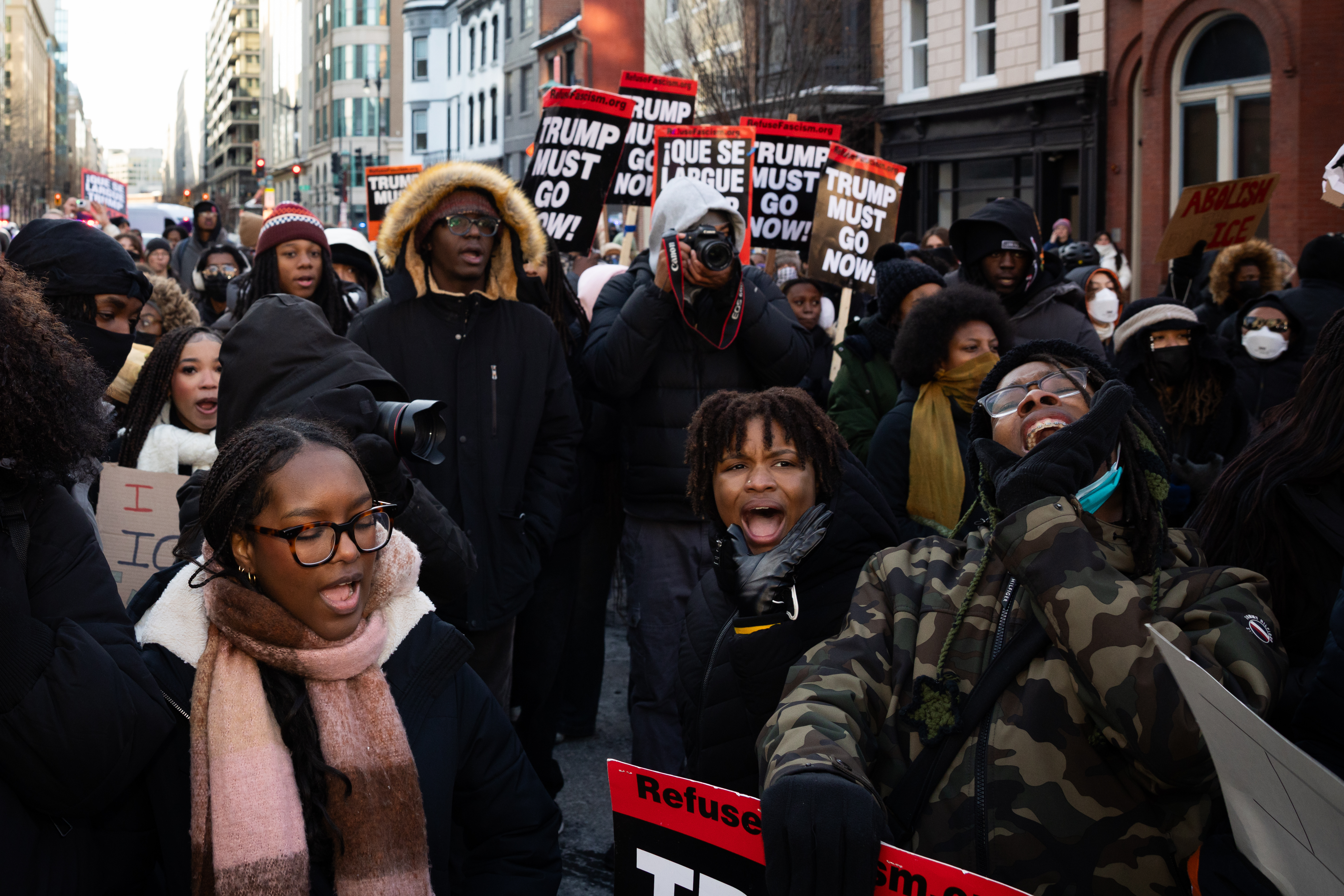 Large crowd of protesters marching in urban street with signs calling for political action during winter demonstration