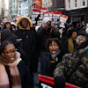 Large crowd of protesters marching in urban street with signs calling for political action during winter demonstration