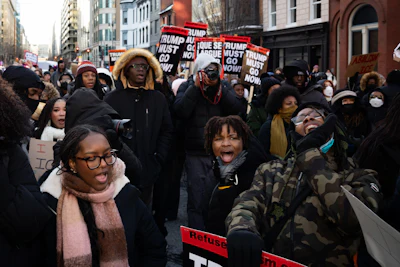 Large crowd of protesters marching in urban street with signs calling for political action during winter demonstration