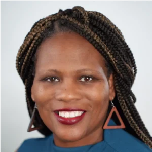 Professional headshot of a smiling woman with braided hair wearing a blue top and triangular earrings