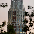Tall Gothic Revival tower with red brick and white stone detailing, featuring multiple spires and arched windows