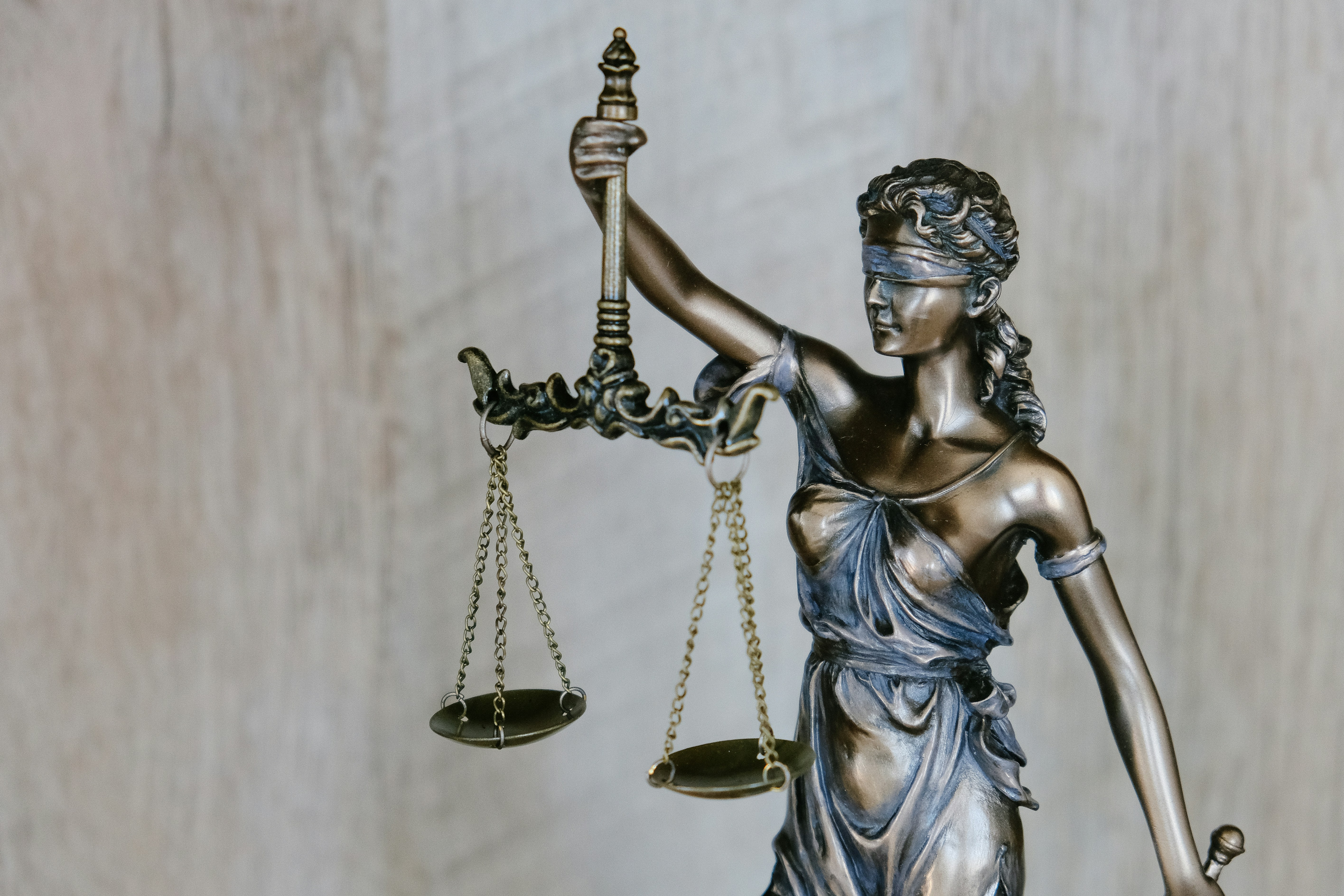 Bronze statue of Lady Justice holding balanced scales and sword, symbolizing law and fairness