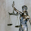 Bronze statue of Lady Justice holding balanced scales and sword, symbolizing law and fairness