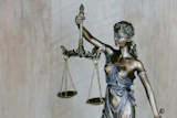 Bronze statue of Lady Justice holding balanced scales and sword, symbolizing law and fairness