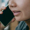 Person in brown turtleneck holding smartphone to ear during phone call