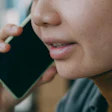 Person in brown turtleneck holding smartphone to ear during phone call