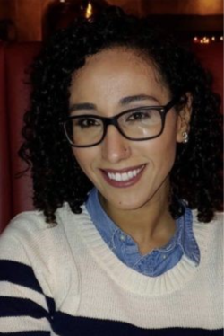Smiling woman wearing glasses and striped sweater in warm indoor setting