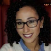Smiling woman wearing glasses and striped sweater in warm indoor setting