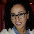 Smiling woman wearing glasses and striped sweater in warm indoor setting