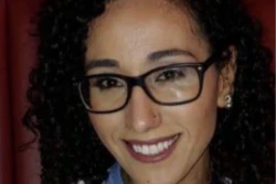 Smiling woman wearing glasses and striped sweater in warm indoor setting