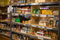 Food pantry shelves stocked with canned goods, pasta, potatoes, and packaged items organized by category