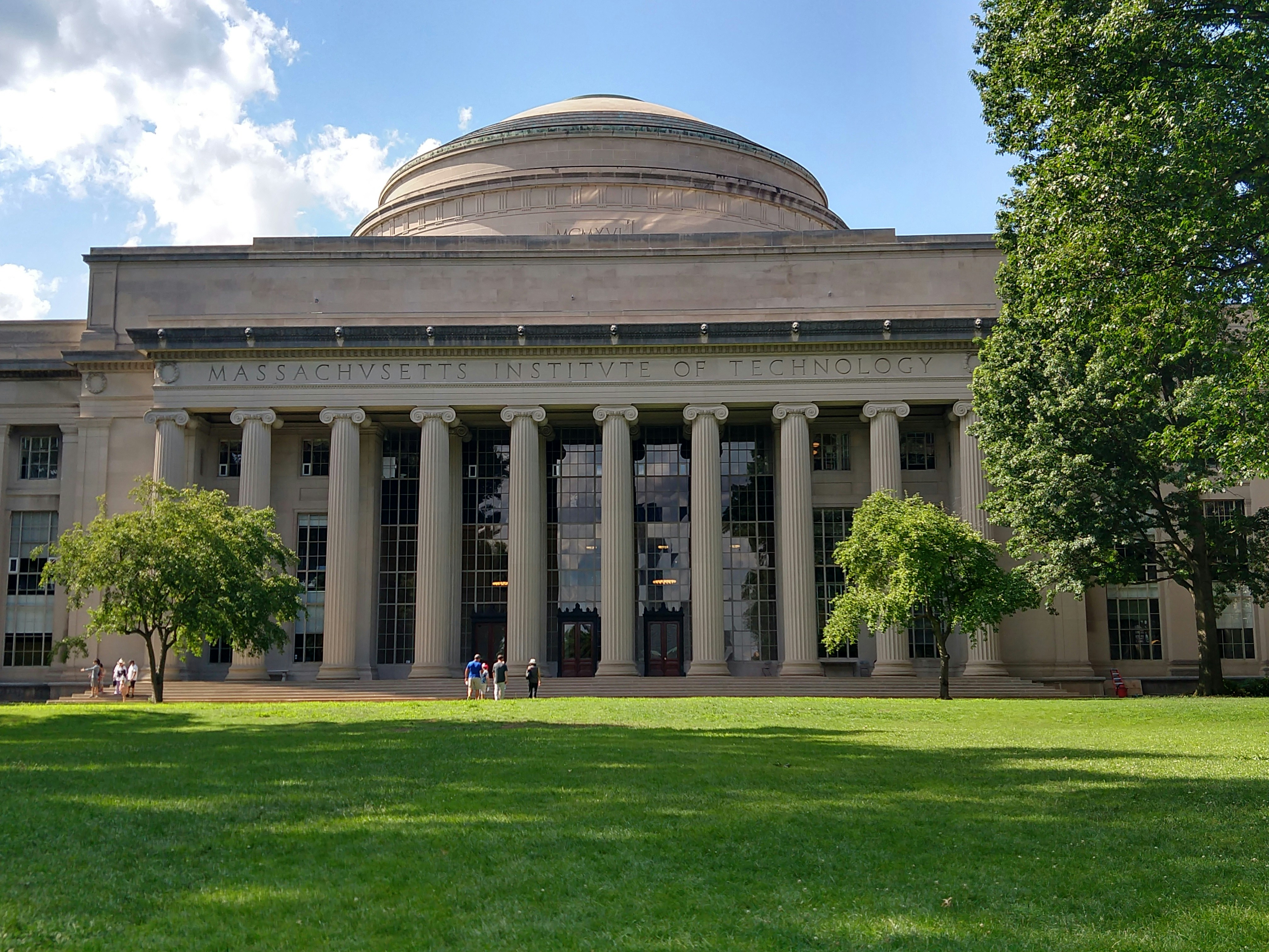 MIT's iconic domed building with classical columns and manicured lawn on a sunny day