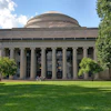 MIT's iconic domed building with classical columns and manicured lawn on a sunny day