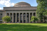 MIT's iconic domed building with classical columns and manicured lawn on a sunny day