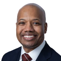 Professional headshot of a smiling man in business attire with dark suit and burgundy tie