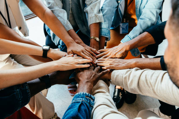 Diverse team members stacking hands together in unity circle from overhead view