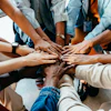 Diverse team members stacking hands together in unity circle from overhead view