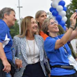 Group of people smiling while taking a selfie at an outdoor event decorated with blue and white balloons