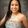 Professional portrait of a smiling woman wearing a patterned strapless dress and beaded necklace with pearl earrings