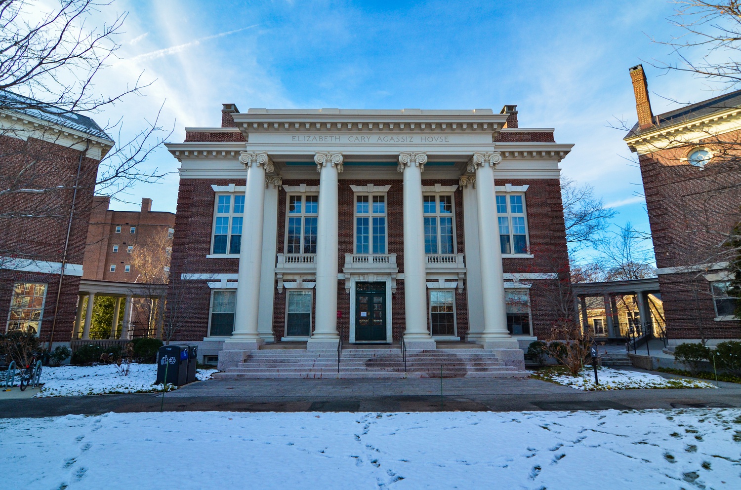 Classical brick building with white columns and blue windows on snowy campus grounds
