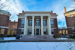 Classical brick building with white columns and blue windows on snowy campus grounds