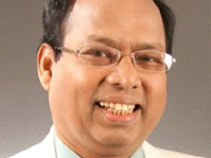 Professional headshot of a smiling man wearing glasses and a light blue shirt Headshot