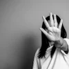 Person with hand raised in stop gesture, face obscured, black and white portrait