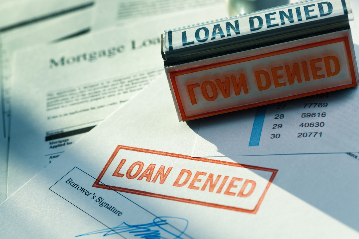 Red 'LOAN DENIED' stamps on mortgage and financial documents with borrower signatures