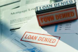 Red 'LOAN DENIED' stamps on mortgage and financial documents with borrower signatures