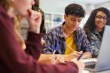 Diverse students collaborating on a group project with laptop in classroom setting