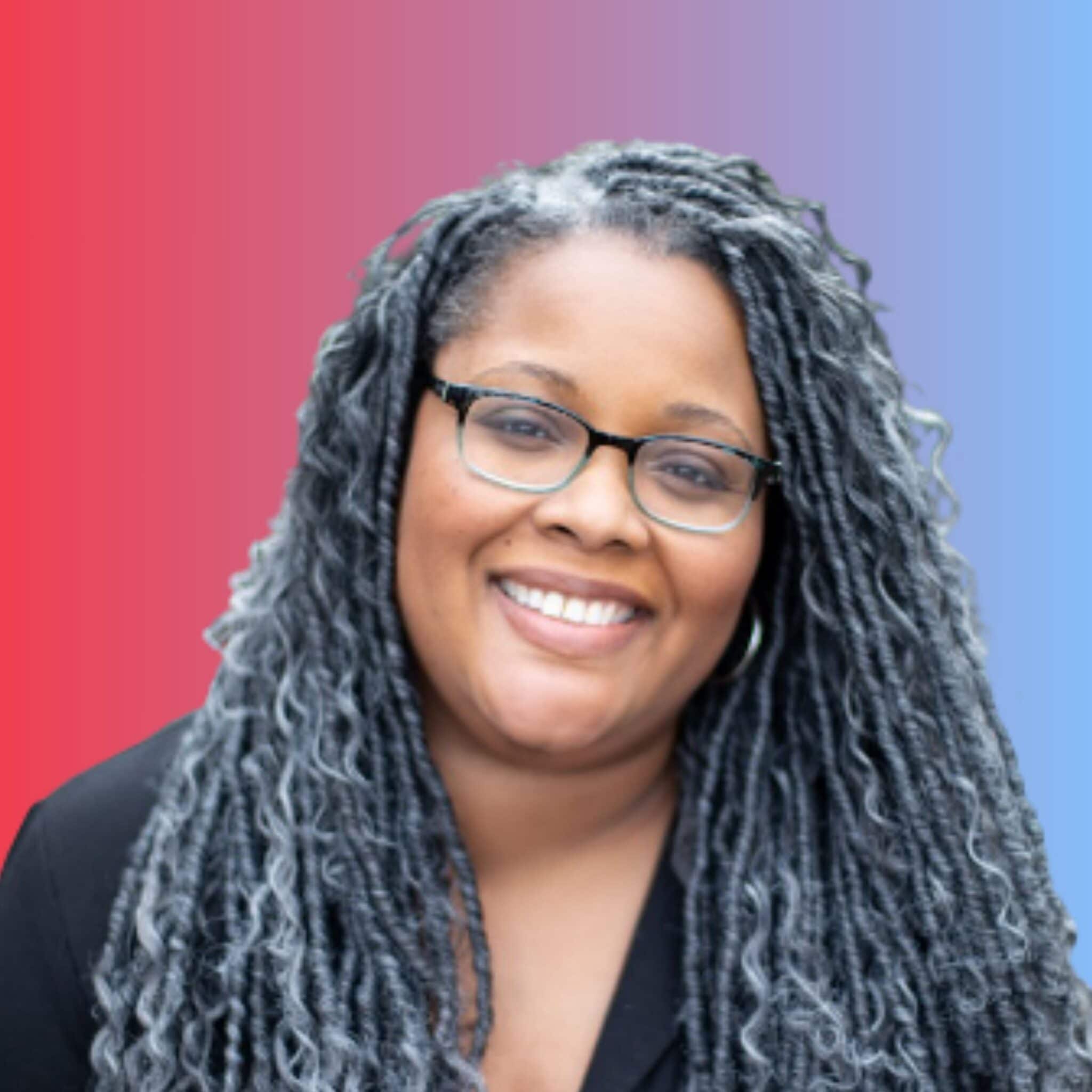 Professional headshot of a woman wearing glasses and black blazer against gradient background