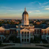 Golden dome university building with red brick architecture and symmetrical wings photographed at sunset