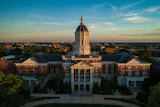 Golden dome university building with red brick architecture and symmetrical wings photographed at sunset