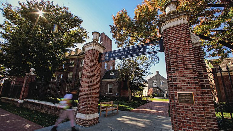 Lafayette College brick gateway entrance with ornate towers flanking a tree-lined campus path