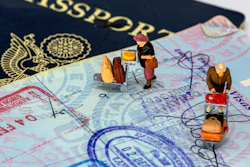 Miniature travelers with luggage positioned on passport pages and currency, illustrating international travel and immigration concepts