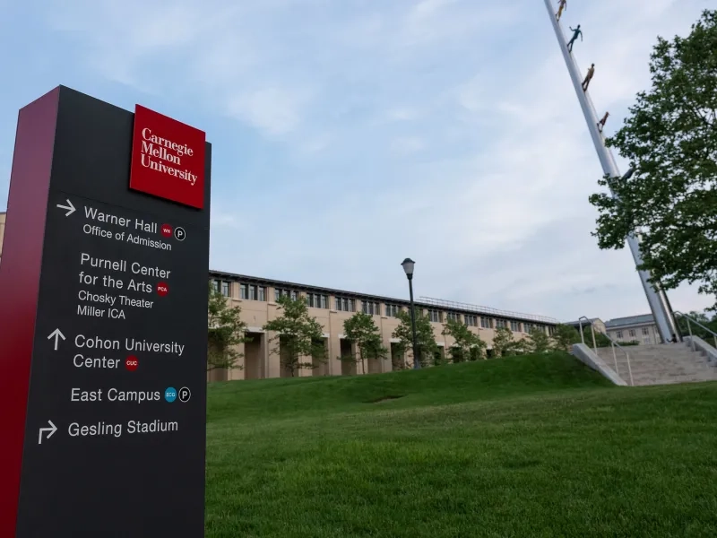 Carnegie Mellon University directional wayfinding sign on campus green space with building and sky in background