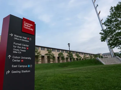 Carnegie Mellon University directional wayfinding sign on campus green space with building and sky in background