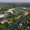 Aerial view of suburban community with orange institutional buildings, residential homes, tree-lined streets, and river at dusk