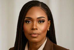 Professional headshot of woman in brown blazer and cream shirt against neutral background
