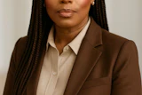 Professional headshot of woman in brown blazer and cream shirt against neutral background