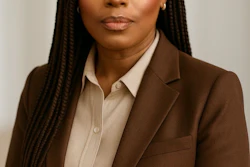 Professional headshot of woman in brown blazer and cream shirt against neutral background