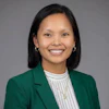 Professional headshot of a smiling woman wearing a green blazer and white striped shirt