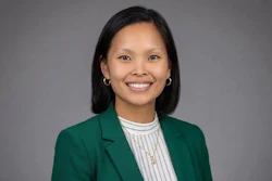 Professional headshot of a smiling woman wearing a green blazer and white striped shirt