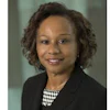 Professional headshot of a woman in business attire with checkered blouse and dark blazer